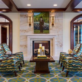 A stylish living room featuring patterned chairs, a central table with candles, and a fireplace adorned with artwork.