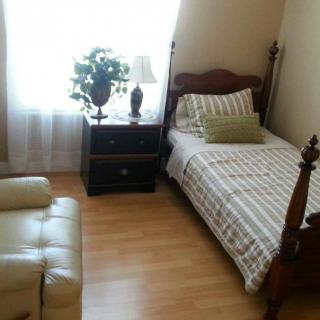 A cozy bedroom with a single bed, nightstand, and natural lighting.