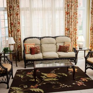 A cozy living room with a wicker furniture set, adorned with floral patterned curtains and a matching rug.