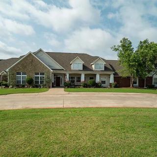A suburban home with a spacious lawn and driveway under a partly cloudy sky.