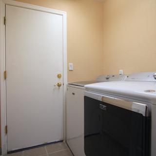 A small laundry room with a washer and dryer next to a closed door.