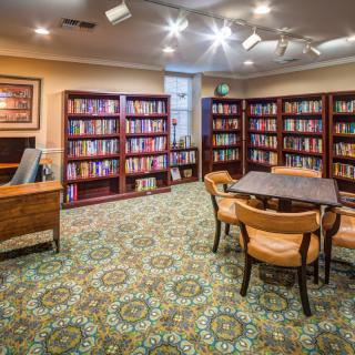 A cozy library reading room with bookshelves, a table, and chairs.