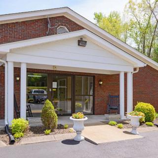 A brick building with a white-columned entrance and landscaped plants.