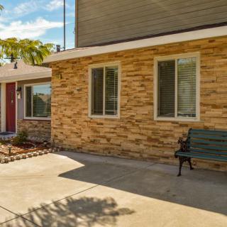 A brick facade house with a driveway and bench in the front yard.