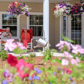 A cozy porch with hanging flower baskets, surrounded by a colorful garden.