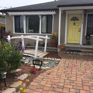Charming house with a yellow door and a small garden bridge.