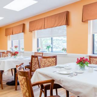A bright dining area with neatly set tables and floral centerpieces.