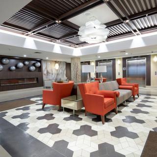A modern lobby with a stylish seating area featuring orange chairs and a chandelier.