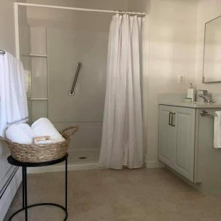 A minimalist bathroom with a shower, vanity, and neatly arranged towels.