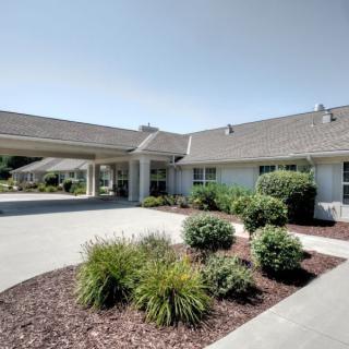 A well-maintained building with a landscaped driveway and green plants under a clear sky.