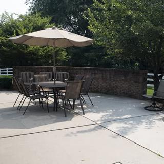 A sunny patio with a table, chairs, and an umbrella set up for outdoor relaxation.
