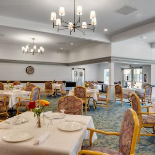 An elegant dining room featuring chandeliers and neatly arranged tables and chairs.
