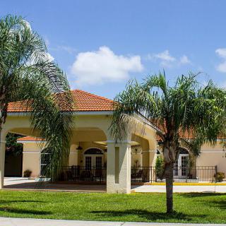 A sunny day view of a residential house with palm trees in the front yard.