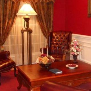 A classic living room setting with red walls, a wooden table, and leather chairs.