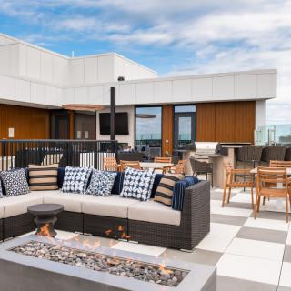 Modern rooftop patio with comfortable seating and a fire pit.