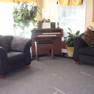A cozy living room with a piano, armchairs, and plants.