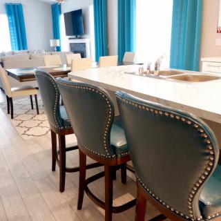 Modern kitchen area with bar stools and blue accents.
