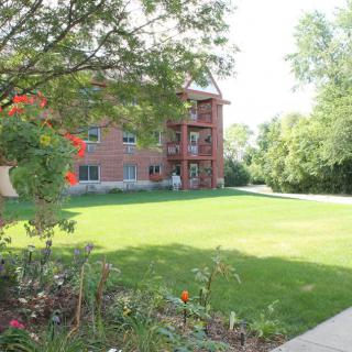 A brick building surrounded by a lush green lawn and trees.