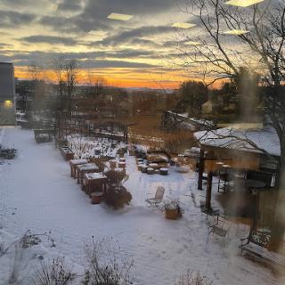 A serene winter sunset illuminates a snowy landscape, creating a tranquil atmosphere.