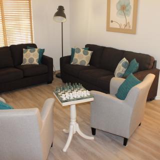 A cozy living room with sofas and armchairs, featuring a chess board on the table.