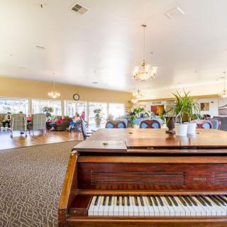 A spacious living room featuring a classic piano and elegant chandeliers.