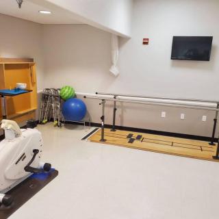 A physical therapy room equipped with parallel bars and an exercise bike.