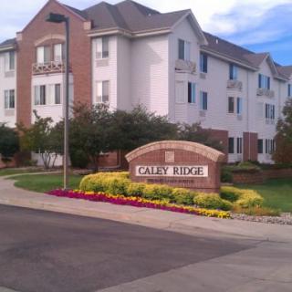 Residential apartment complex with a landscaped garden and sign.
