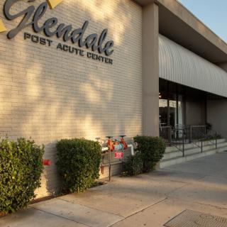 The entrance to Glendale Post Acute Center, featuring a sidewalk and greenery.