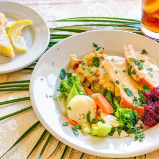 A plate of chicken with mixed vegetables and a side salad, served with lemon wedges.