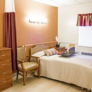 A cozy bedroom with a bed, chair, dresser, and window.