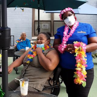 Residents enjoy a tropical-themed outdoor gathering, complete with leis and refreshments.