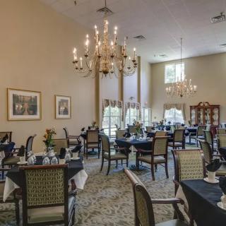 An elegant dining room with chandeliers and neatly arranged tables and chairs.