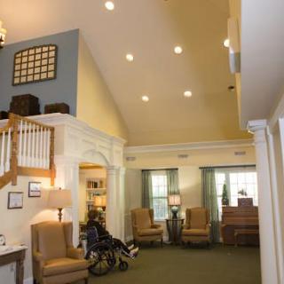 A spacious living room with high ceilings, comfortable seating, and large windows.