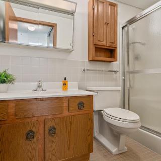 A well-lit bathroom featuring a wooden vanity, a shower, and essential fixtures.