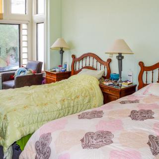 A cozy bedroom with twin beds, matching lamps on bedside tables, and a large window providing natural light.