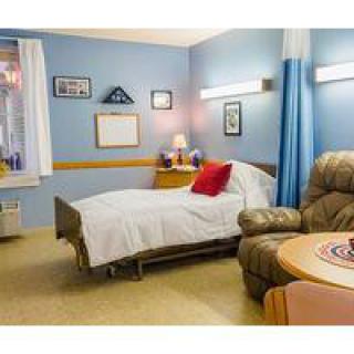 A comfortable hospital room with a bed, recliner, and various decorations.