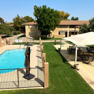 A backyard view featuring a swimming pool, lawn, and patio area with outdoor seating.