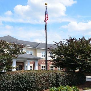 A neatly landscaped building with an American flag flying in front under a partly cloudy sky.