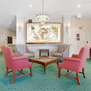 A cozy lobby with a seating area featuring four chairs around a wooden table, enhanced by a large artwork on the wall.
