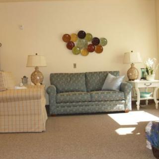 A cozy living room with a blue sofa, accented by two lamps and colorful wall art.