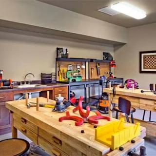 A well-equipped workshop featuring multiple workbenches and various tools for woodworking and crafting.