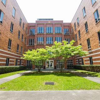 A brick building with a central courtyard featuring a tree and well-maintained grass.