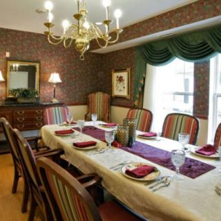 A formal dining room with a chandelier, elegantly set table, and striped chairs.