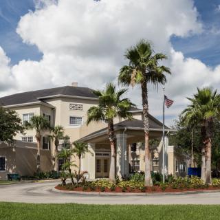 A hotel surrounded by palm trees with a cloudy sky in the background.