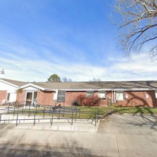 A single-story brick house with a wheelchair ramp and clear blue sky.