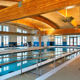 An indoor swimming pool featuring a wooden ceiling and natural lighting.