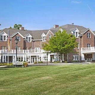 A large residential building with a well-maintained lawn and clear blue sky.
