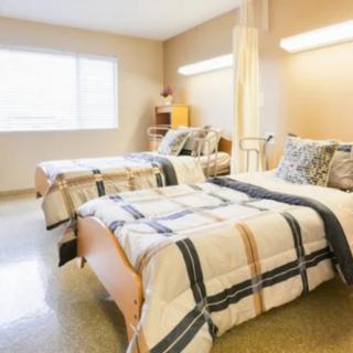 A well-lit healthcare bedroom featuring two neatly made beds with patterned bedding.