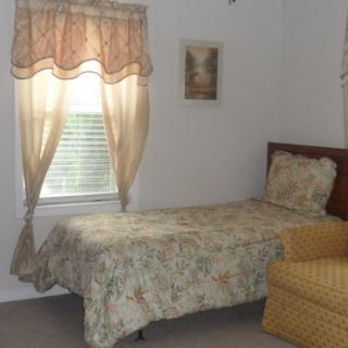A simple bedroom with a single bed and a window with curtains.