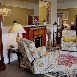 A cozy living room with floral-patterned armchairs, a warm fireplace, decorative carpet, and ambient lighting.